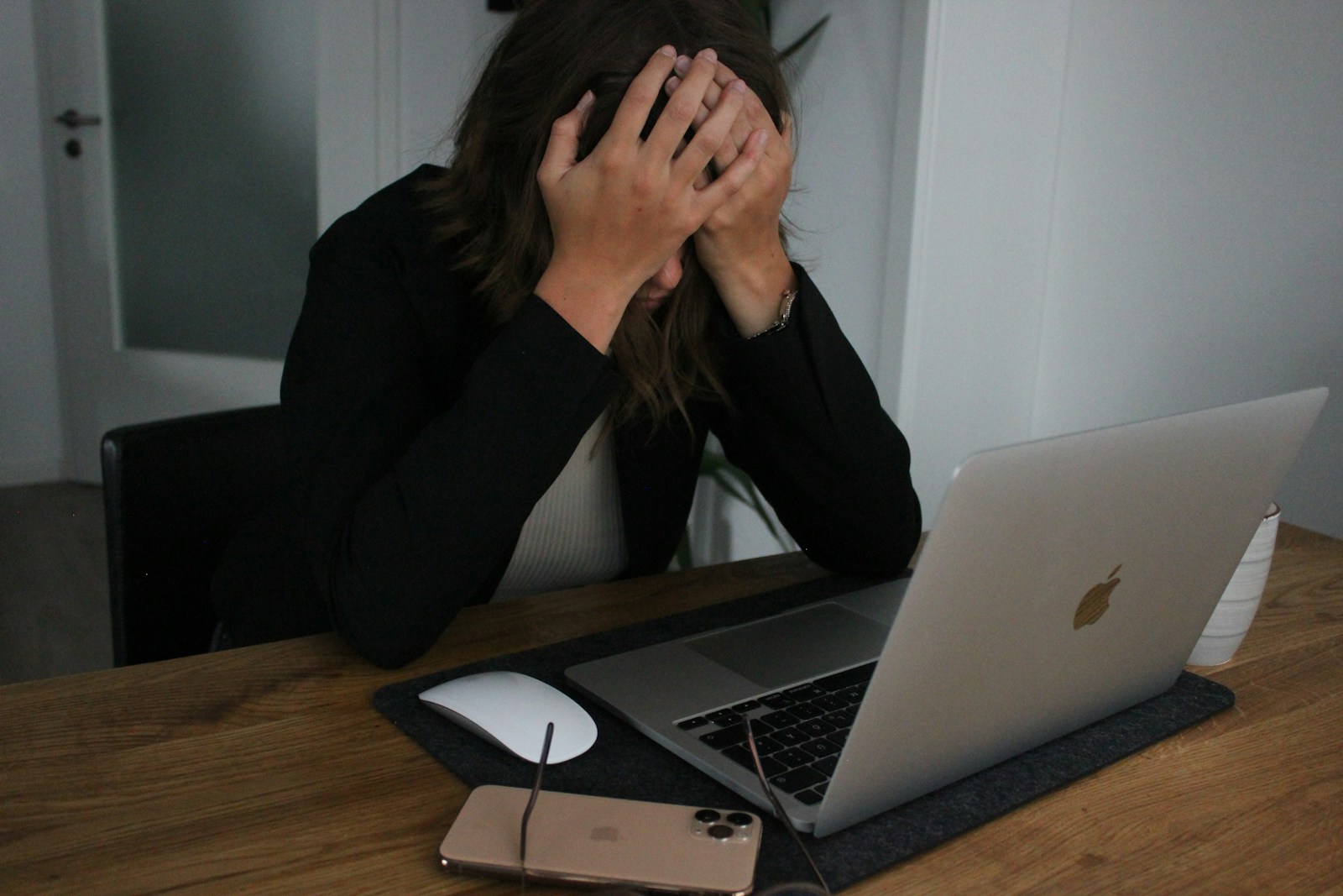 a woman covering her face while looking at a laptop